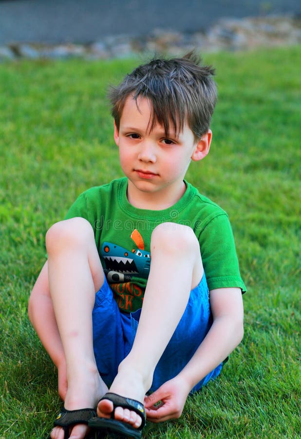 Little boy sits in the grass.