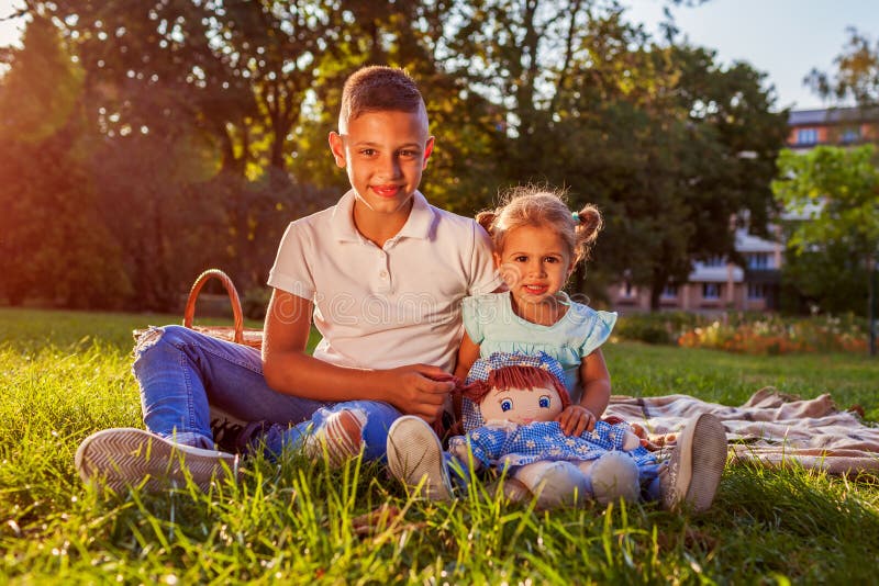 Little boy sitting on grass with his toddler sister in park. Happy family having picnic. Family values royalty free stock photo Little boy sitting on grass with his toddler sister in park. Happy family having picnic. Family values royalty free stock photo