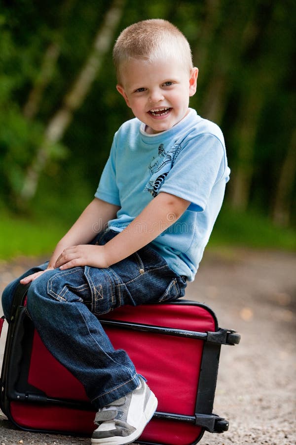 Little boy sitting on his suitcase