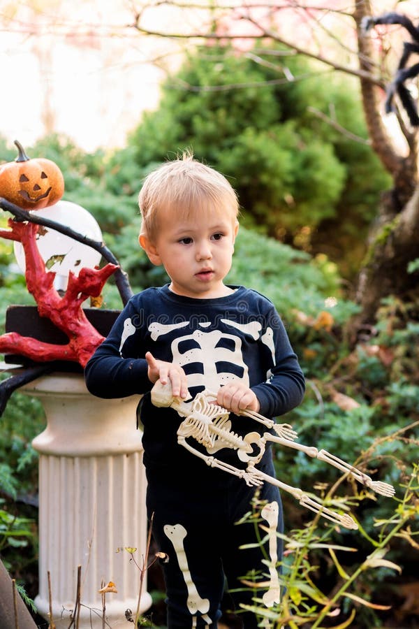 Little Boy in a Skeleton Costume Holding a Skeleton on a Halloween ...