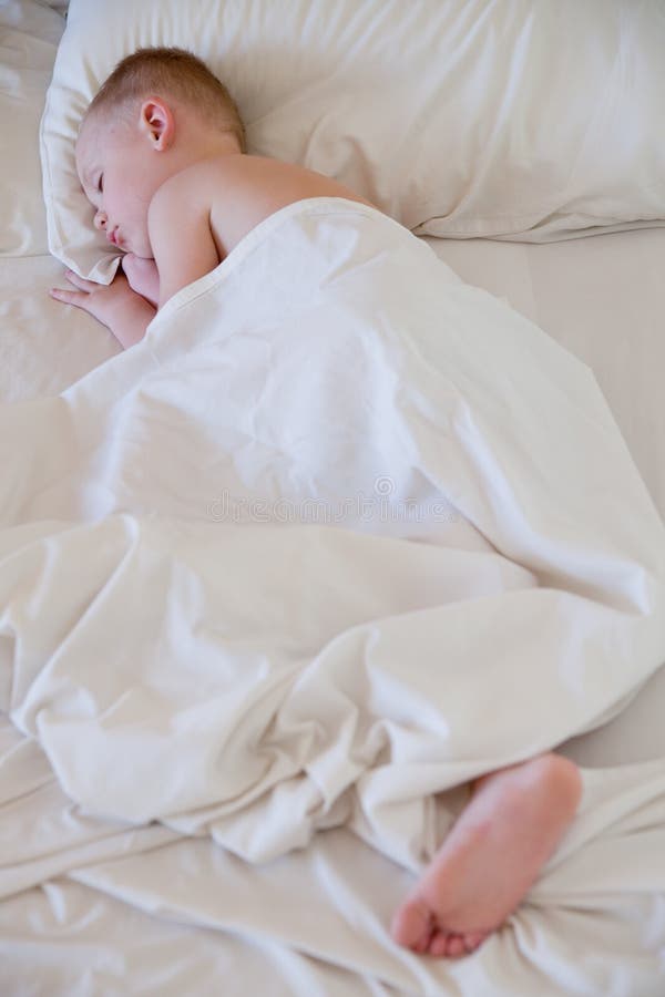 Little boy sleep on white bed.