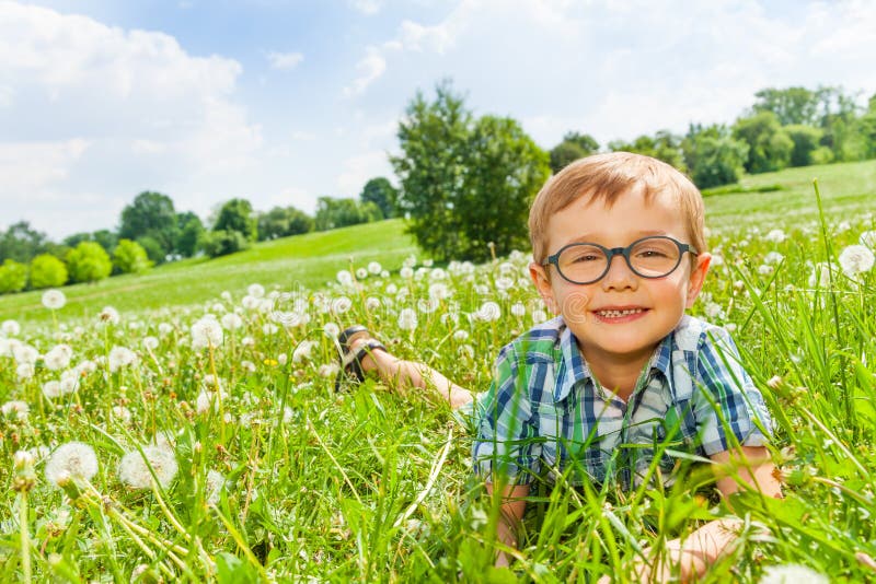 Little boy smiles laying on a grass