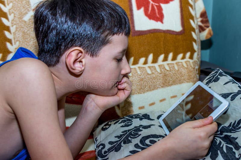 Little Boy som håller ögonen på den digitala minnestavlan med framsidauttryck fotografering för bildbyråer Little Boy som håller ögonen på den digitala minnestavlan med framsidauttryck fotografering för bildbyråer