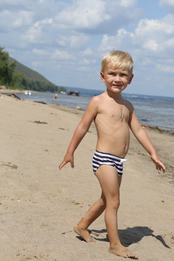 Little boy standing on the beach near the river