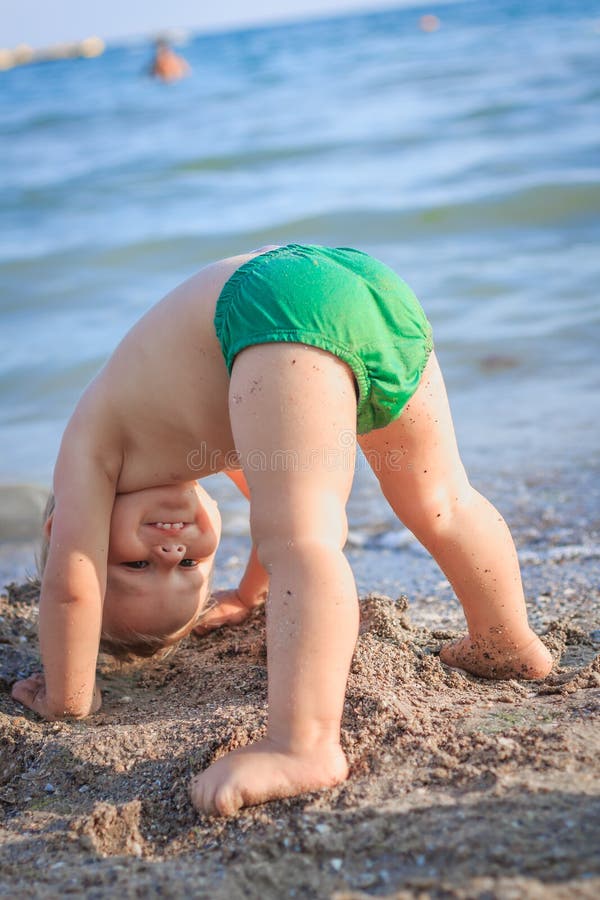 Little boy standing on his head on the beach