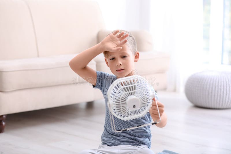 Little boy suffering from heat in front of fan