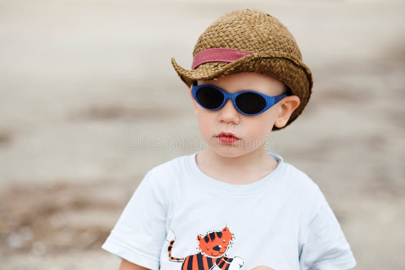 Little boy in sunglasses and a hat outdoors