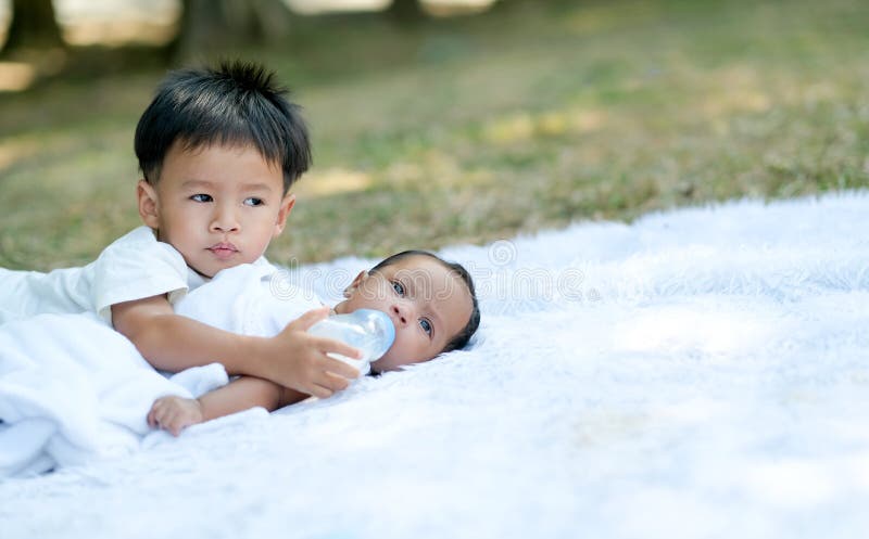 Little Boy Take Care His Little Sister on White Carpet in the Garden ...