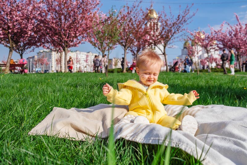 Băiețel care ia aer curat și soare pe o pătură verde moale. stock photography