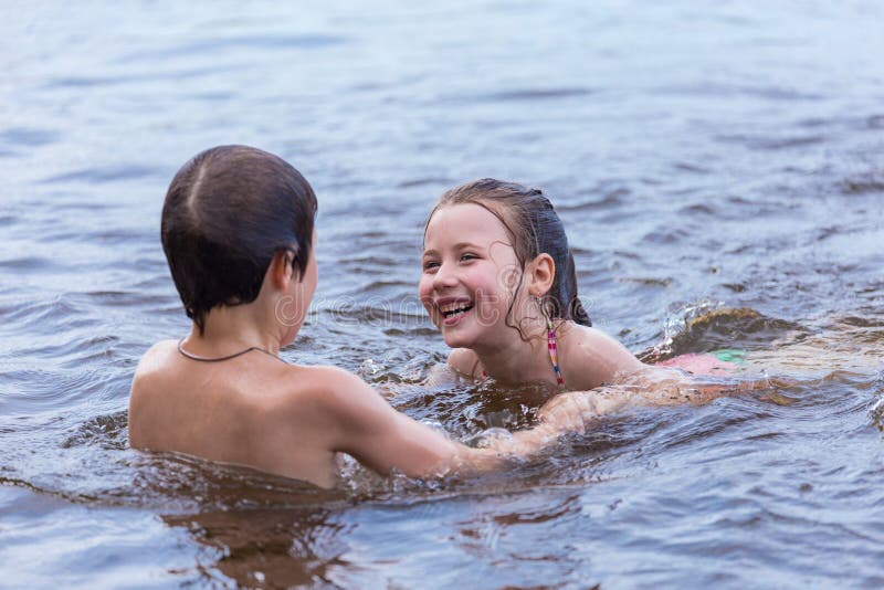 Little boy teaches his little sister to swim in a summer lake stock photos.