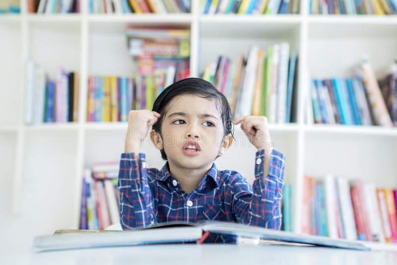 Little boy thinking something in the library stock photography