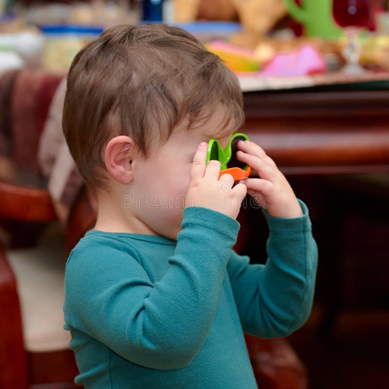 Little Boy Toddler is Playing with Toy Glasses at Dinner Stock Photo