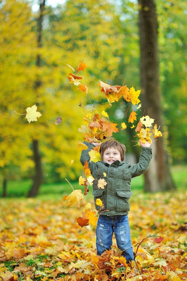 Little boy tossing leaves in autumn park royalty free stock photos