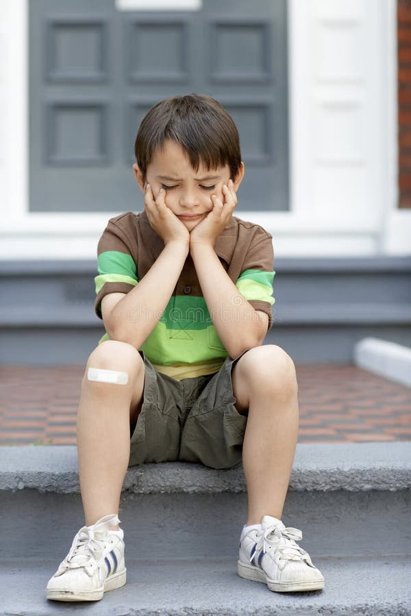 Little Boy triste que senta-se em etapas imagem de stock Little Boy triste que senta-se em etapas imagem de stock