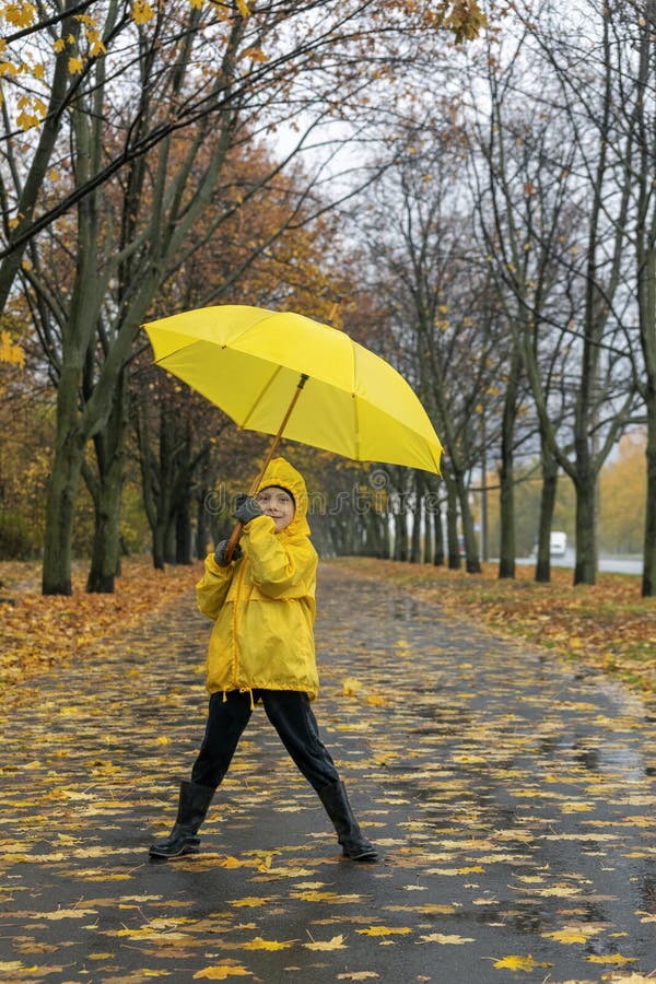 Little boy walks in the park and plays with an yellow umbrella. Walking with child in rain. Vertical frame stock photography
