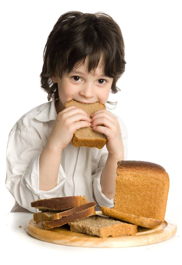 The little boy which eating a bread on desk