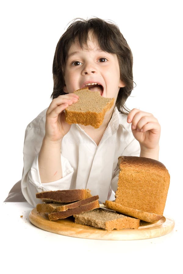 The little boy which eating a bread on desk