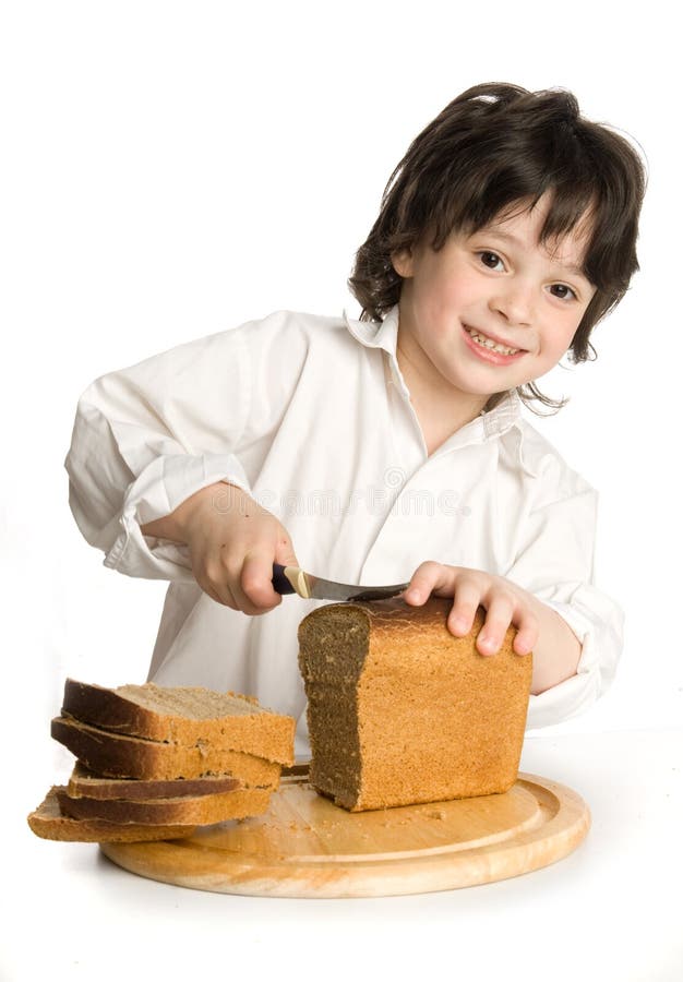The little boy which slicing a bread on desk