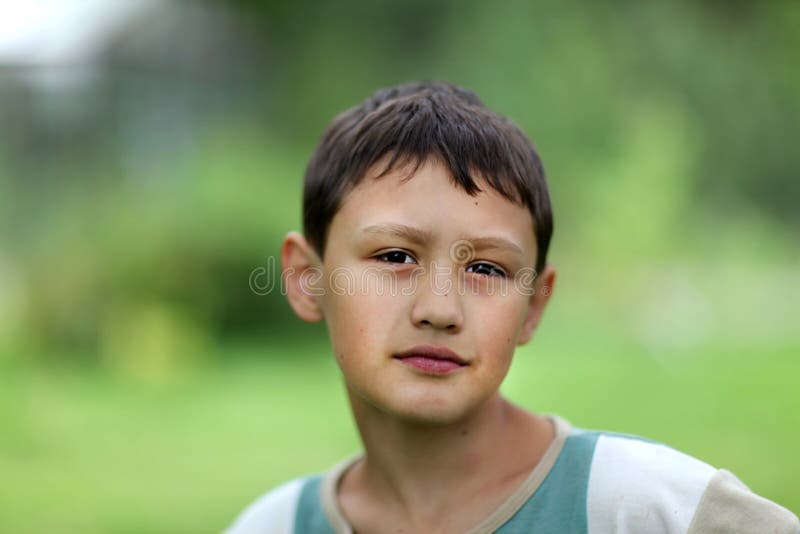 Little boy 10 years old against green grass