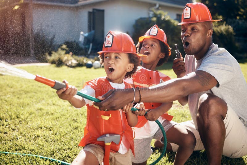 Little boys in firemen costumes. African American father playing with his children. Little boys playing in the garden