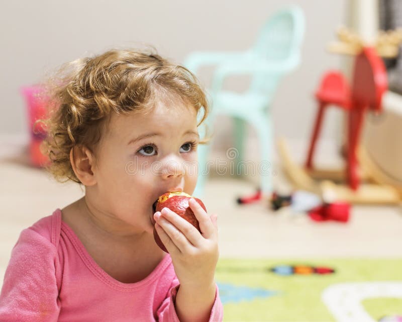 Little Caucasian Baby Girl in Pink Bites an Apple. a Child with Curly Short Hair in the Home Interior, Portrait of a Girl Stock Image - Image of european, little: 166385797 Little Caucasian Baby Girl in Pink Bites an Apple. a Child with Curly Short Hair in the Home Interior, Portrait of a Girl Stock Image - Image of european, little: 166385797