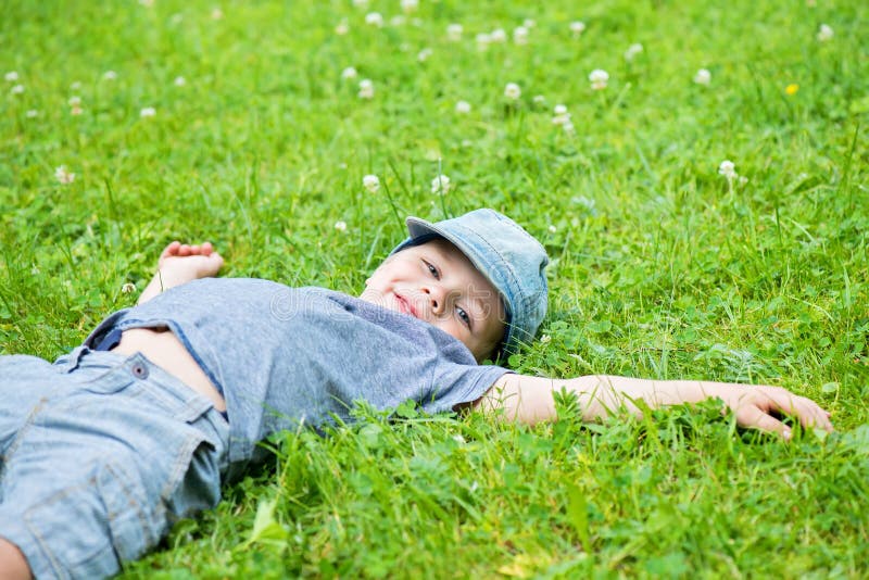 Маленький мальчик лежит. Мальчик лежит на спине. Мальчик лежит на траве. Лежачий мальчик.