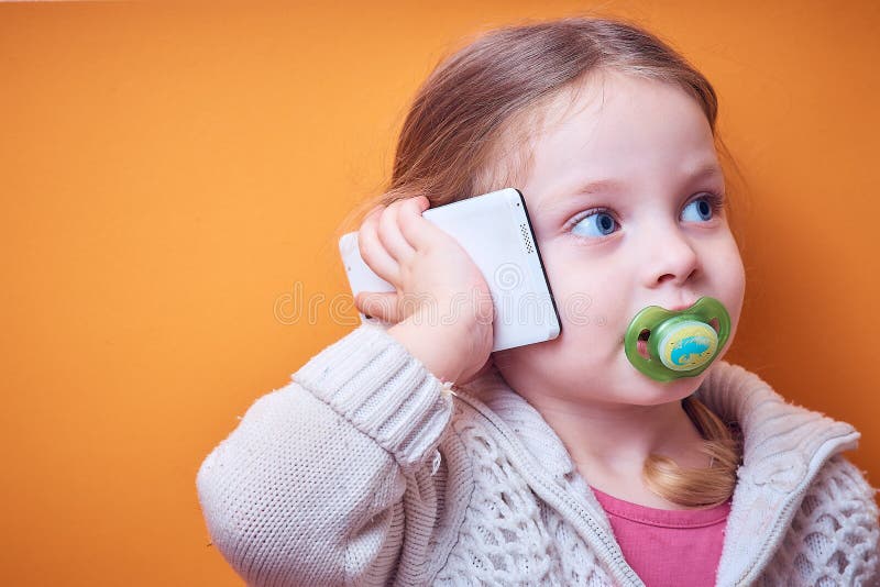 Little Caucasian girl with a phone in her hand on a colored background, a place for text royalty free stock photos Little Caucasian girl with a phone in her hand on a colored background, a place for text royalty free stock photos