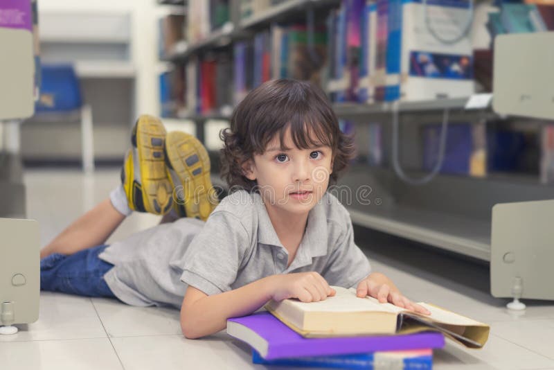 Little child boy laying on floor and reading a book in library. stock images Little child boy laying on floor and reading a book in library. stock images