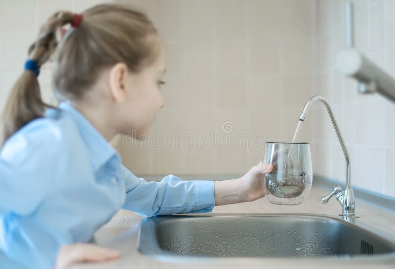 Little child is drinking fresh and pure tap water from glass. Water being poured into glass from kitchen tap. Zero waste and no