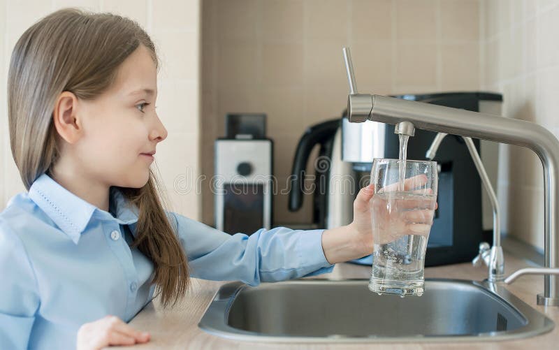 Little child is drinking fresh and pure tap water from glass. Water being poured into glass from kitchen tap. Zero waste and no