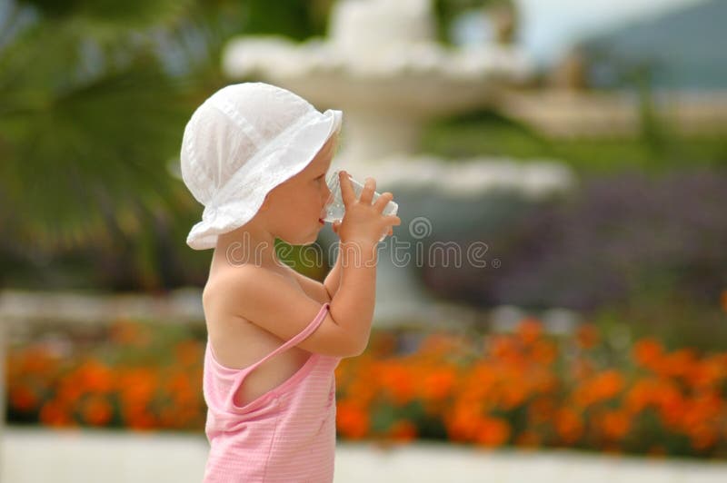 Little child drinking water from glass