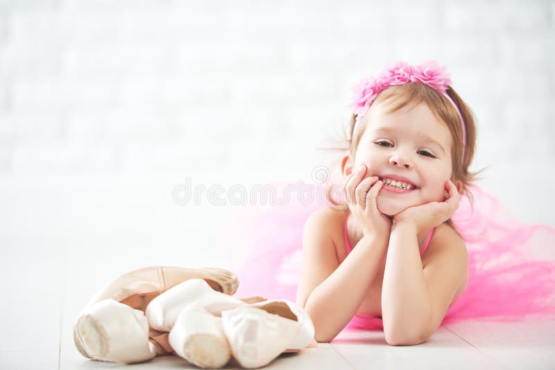 Little child girl dreams of becoming ballerina with ballet shoe