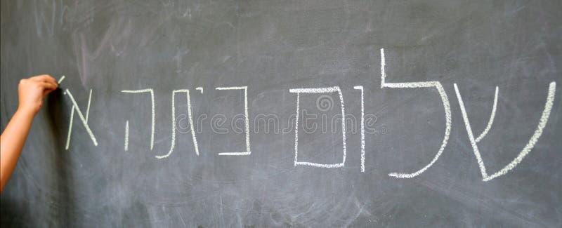 Little child hand writes Hello First Grade greetings in Hebrew