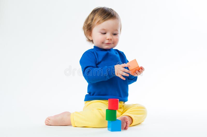 Little child playing with dices on white background