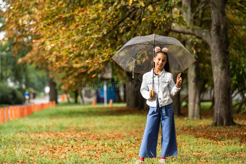 Little child walking with umbrella in the rain in fall park stock photo