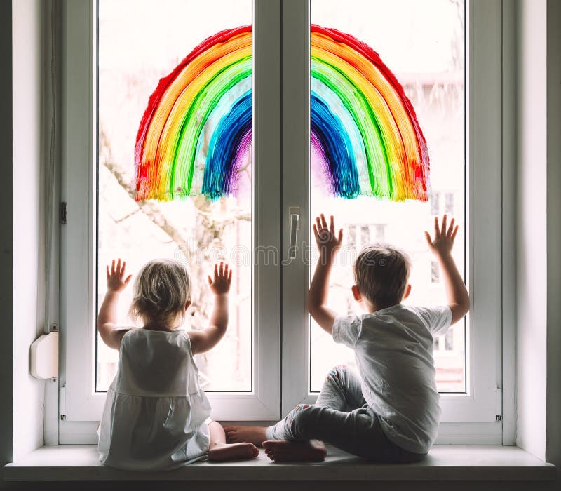 Little children on background of painting rainbow on window.