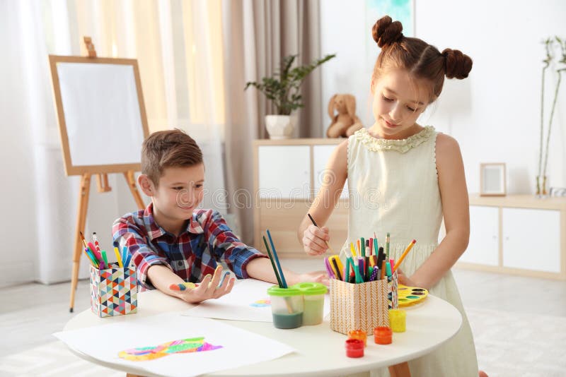 Почему дети красят. Дети рисуют за столом. Фото детей рисующих за столом. Дети красят за столом в садике. Картинка девочка рисует за столом.