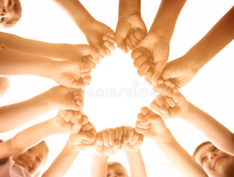 Little children putting their hands together in sunlit room, bottom view. Volunteering with kids