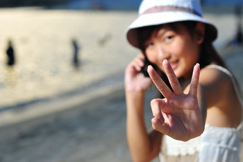 Little Chinese Asian girl on beach with phone