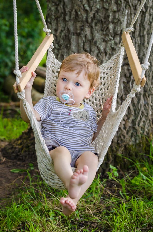 Little cute baby boy riding on hammock swing at park
