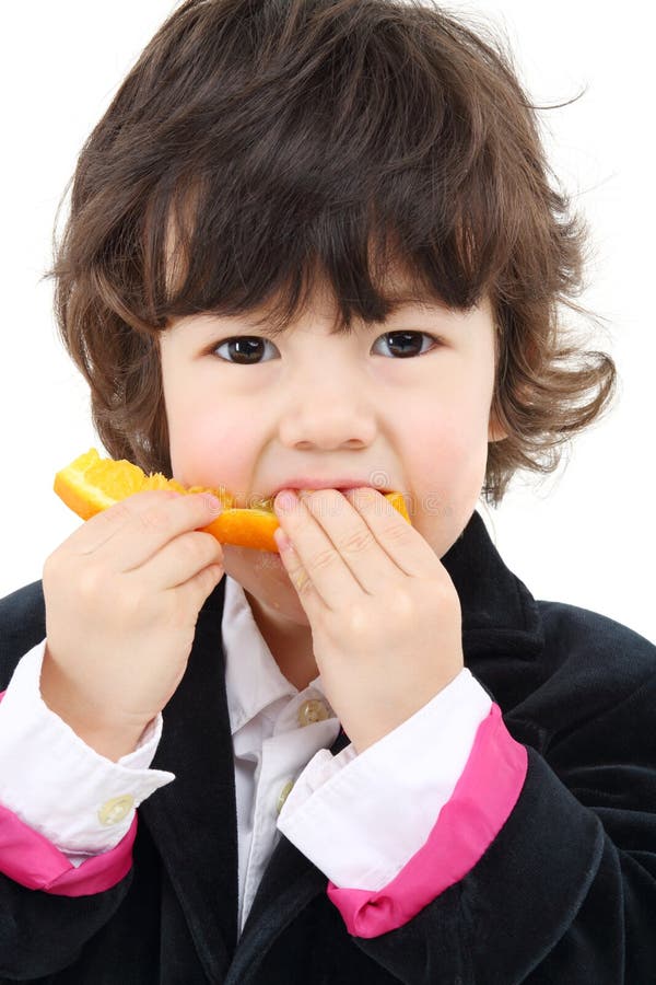 Little cute boy in coat eats orange isolated royalty free stock photos Little cute boy in coat eats orange isolated royalty free stock photos