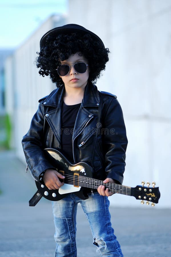 A boy like a rock star playing music on electric guitar.