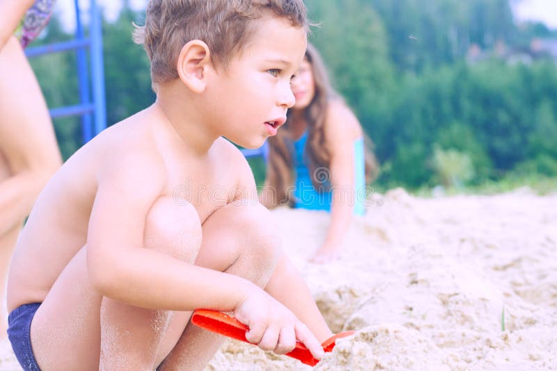 Little cute boy with plastic spatula in hand makes sand castle at the beach. royalty free stock image Little cute boy with plastic spatula in hand makes sand castle at the beach. royalty free stock image