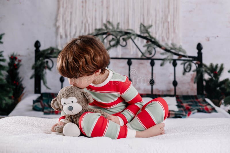 cute-boy-in-striped-pajamas-playing-with-fluffy-monkey-toy-in-bed-with