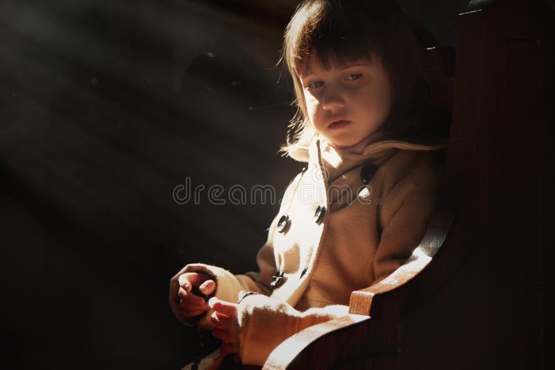 Little cute child girl praying in the church. Faith concept