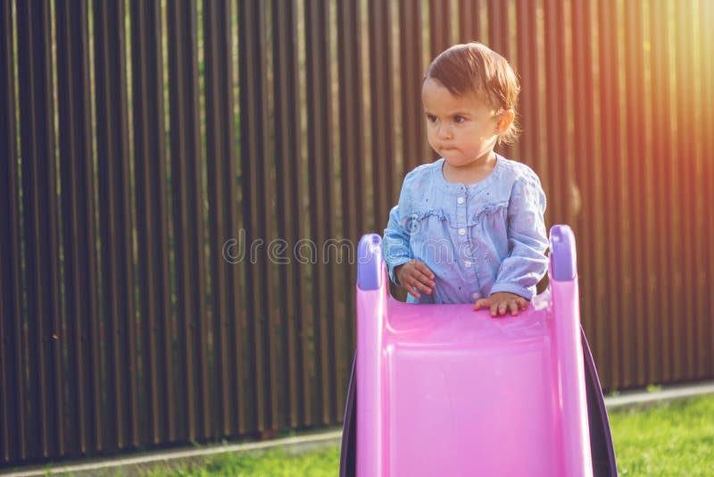 Little and Cute Girl Play on Slide and Make a Grimace while she Plays ...