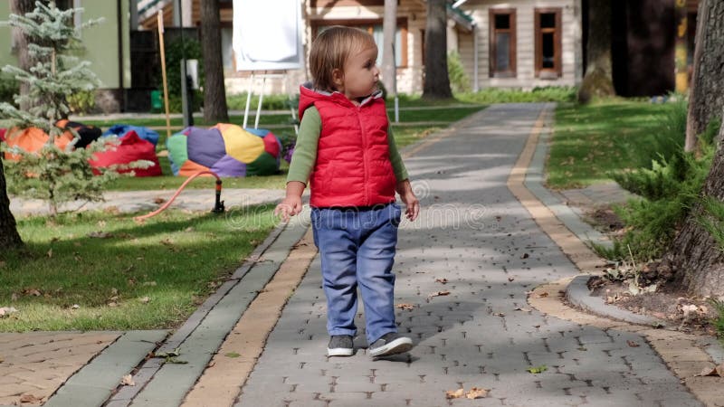 Little cute girl walks along a path in the park. Slow motion stock video footage