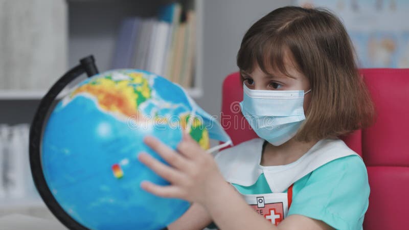 Little cute kid girl doctor puts a mask on the globe of the planet Earth. Save earth planet hands. Our future in your