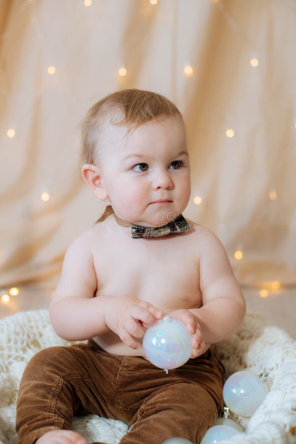 A Little Cute Kid In Suspenders And A Bow Tie Sits In A Basket