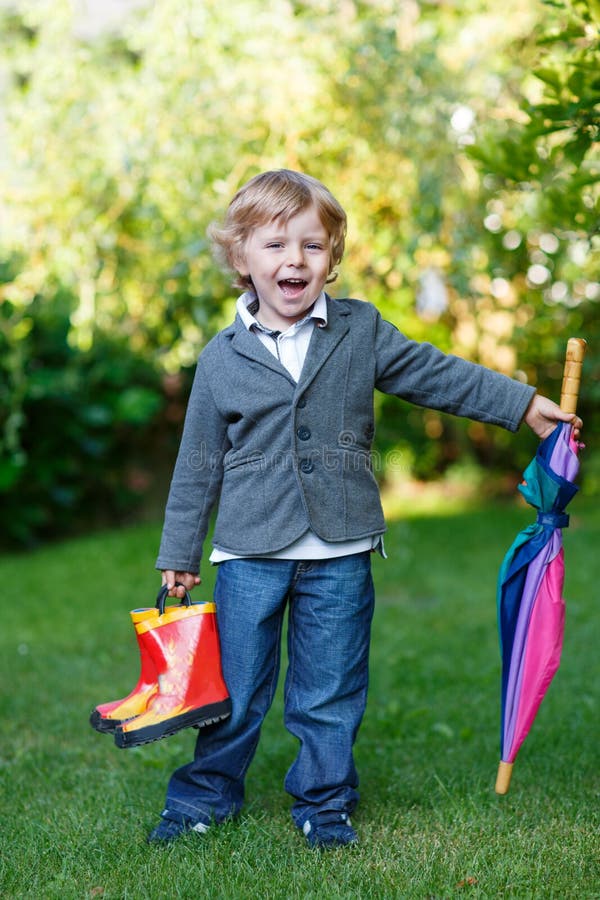 Little cute toddler boy with colorful umbrella and boots in a park. Little cute toddler boy with colorful umbrella and boots in a park